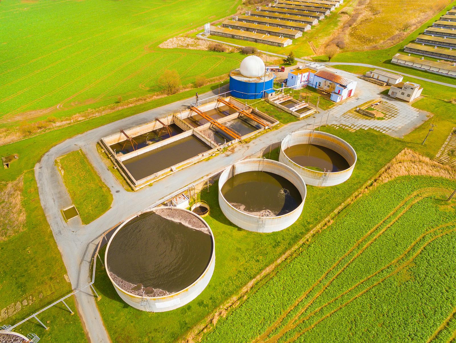 Aerial view of a biogas and wastewater plant – digester tanks, settling basins and a white gas holder dome