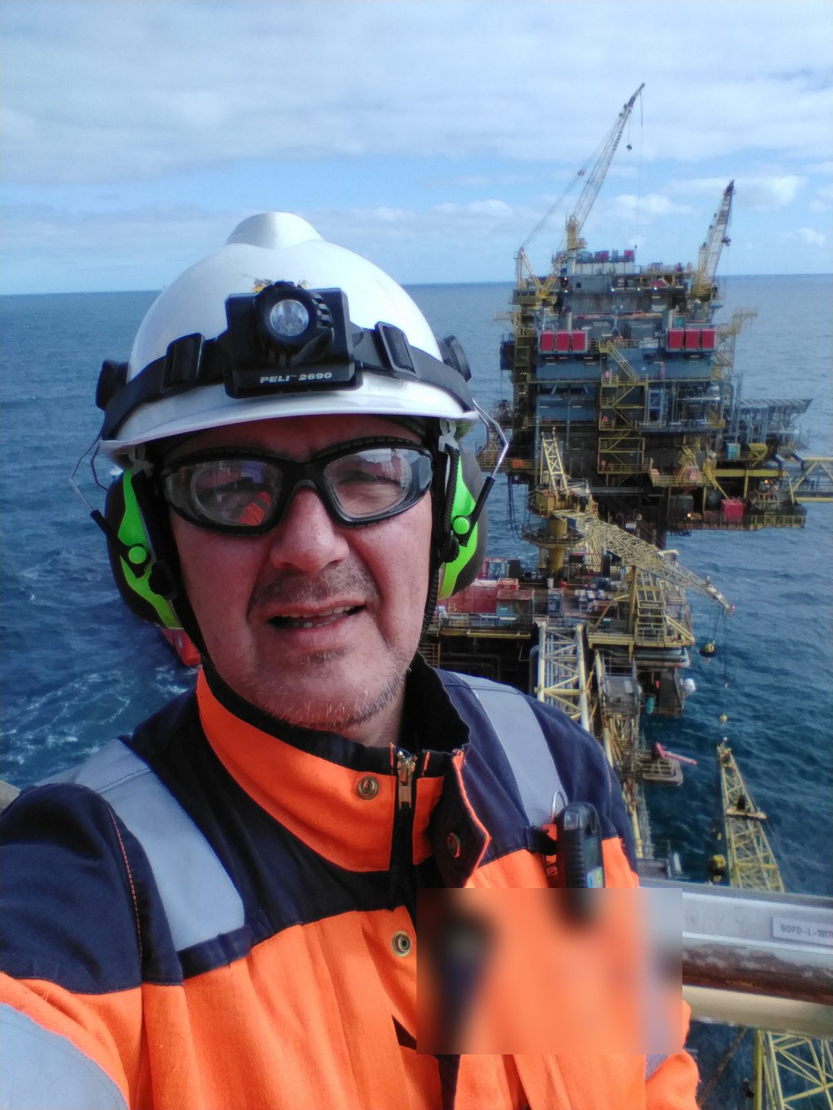 István Giblák on an offshore oil and gas platform, in PPE, with the sea and platform structure in the background