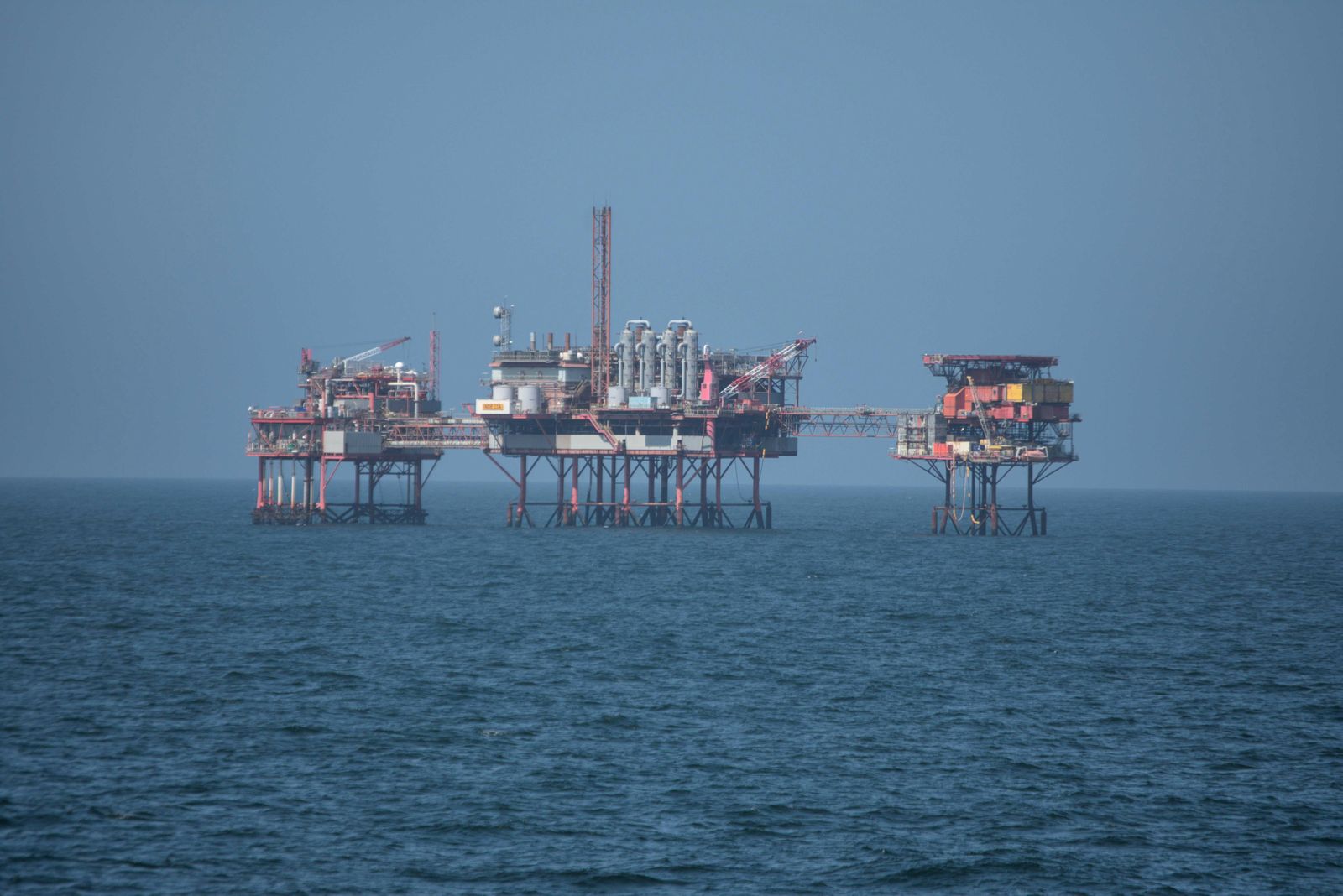 Híddal összekötött offshore olaj- és gázipari platform-komplexum a tengeren, process-modulokkal